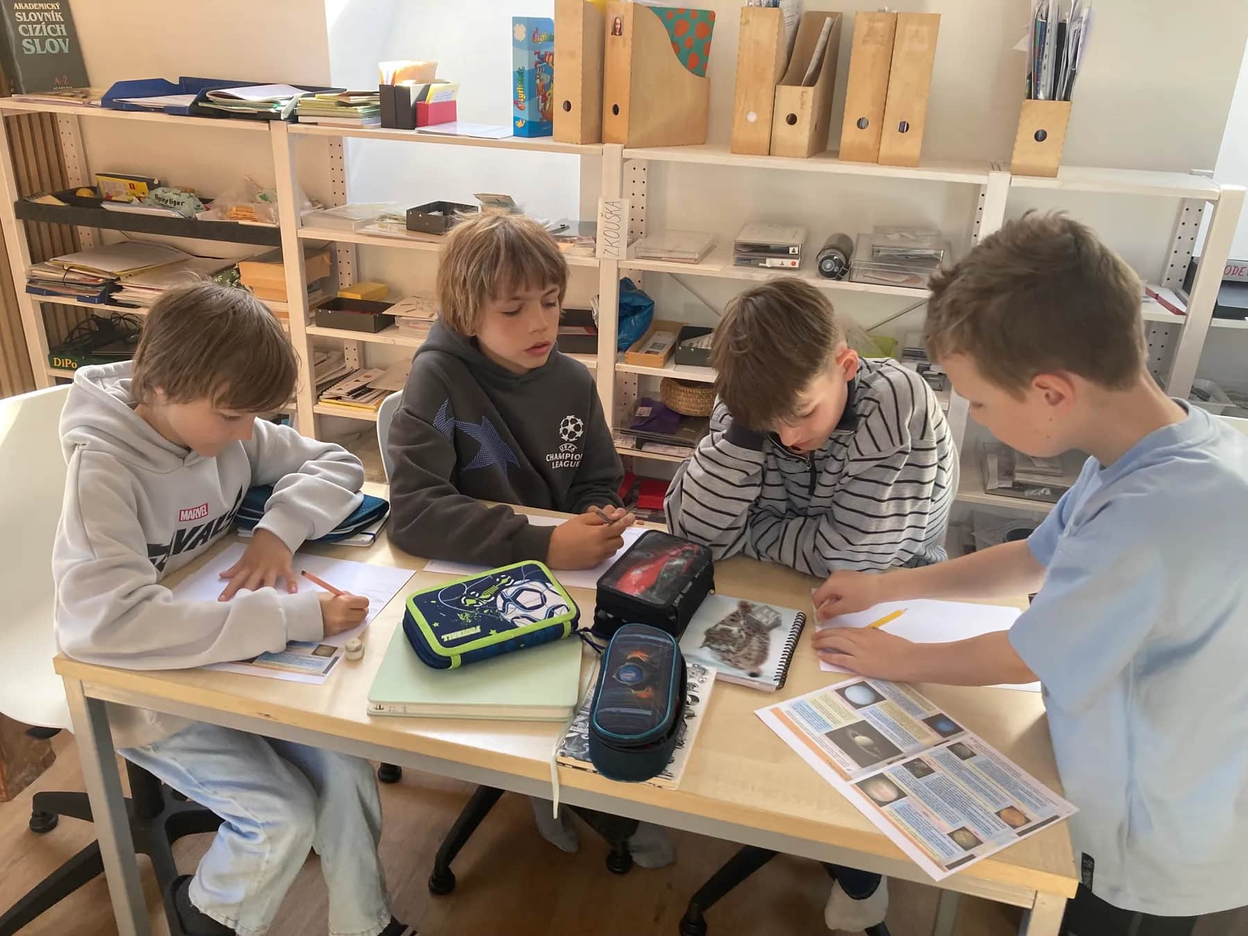 Chlapci u stolu pracují s texty a tabulkami.