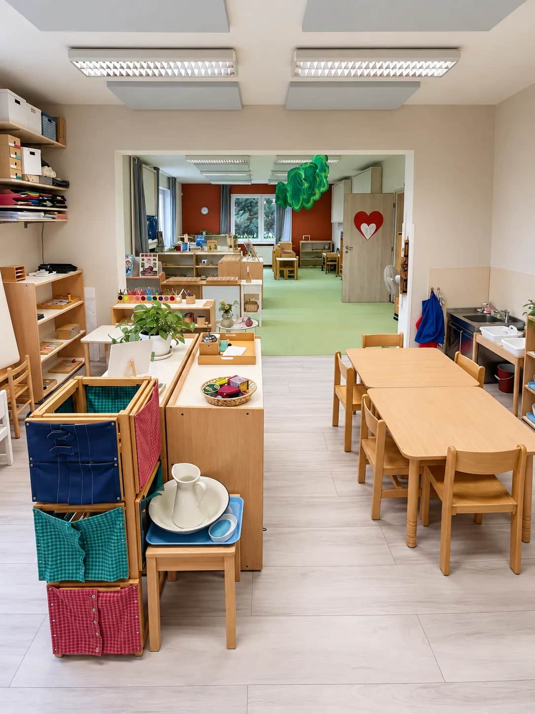 Montessori třída s nízkými stolky, židličkami a poličkami s pomůckami.