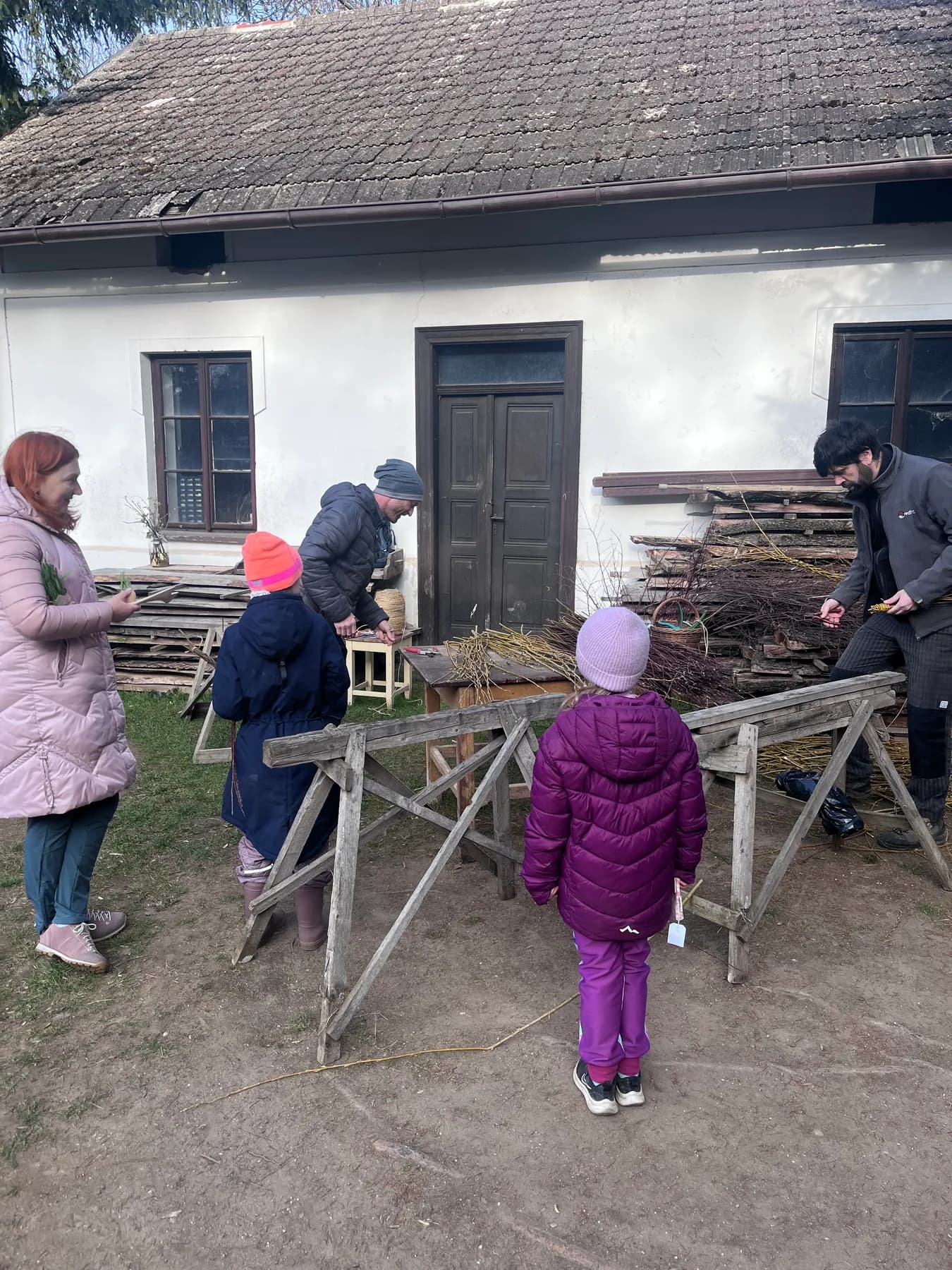 Dospělí a děti společně pracují na opravě starého stavení v areálu v Kuří.