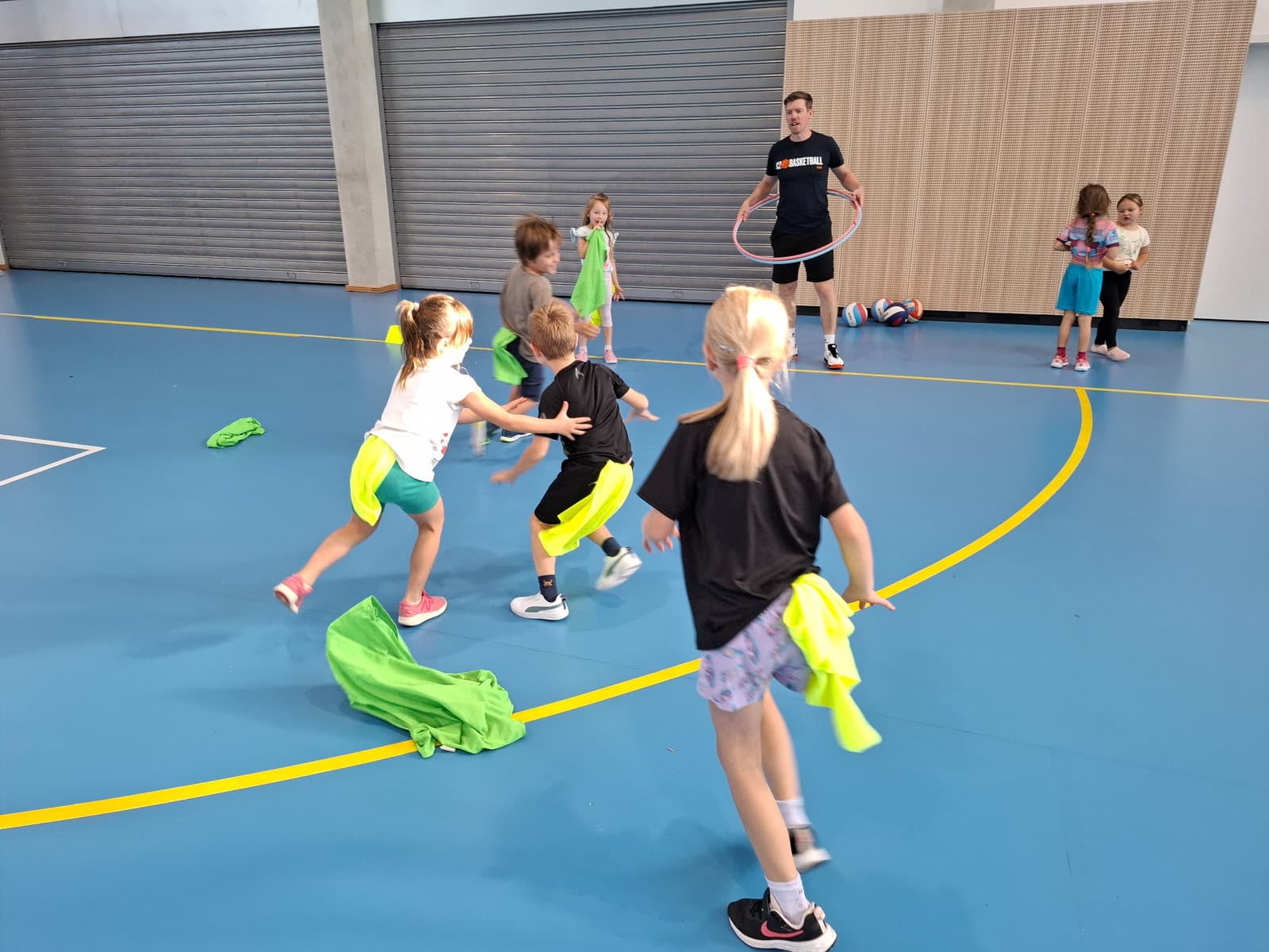 Děti ze ZŠ Sofie hrají pohybovou hru s barevnými rozlišováky při basketbalových aktivitách.