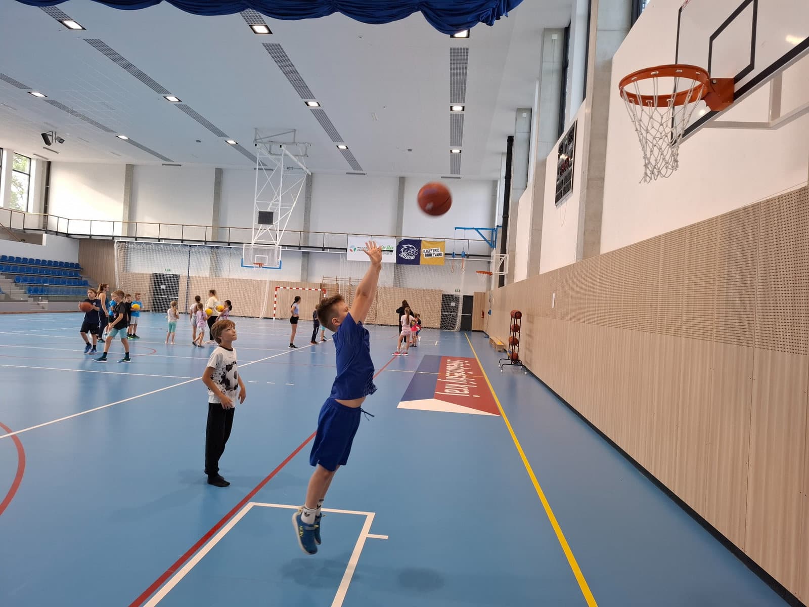 Žák ZŠ Sofie střílí basketbalovým míčem na koš během sportovního programu.